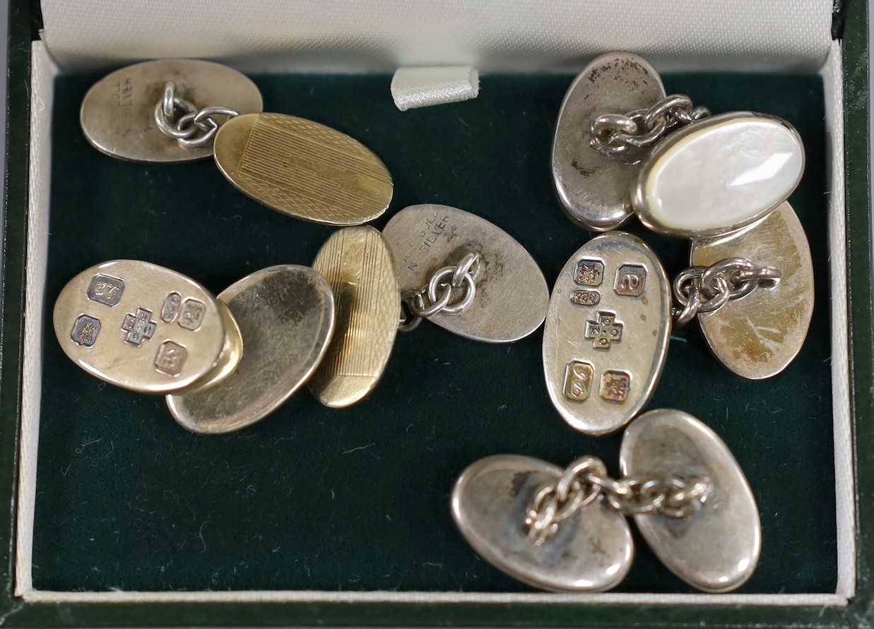 A pair of modern silver oval cufflinks and two other pairs of cufflinks.